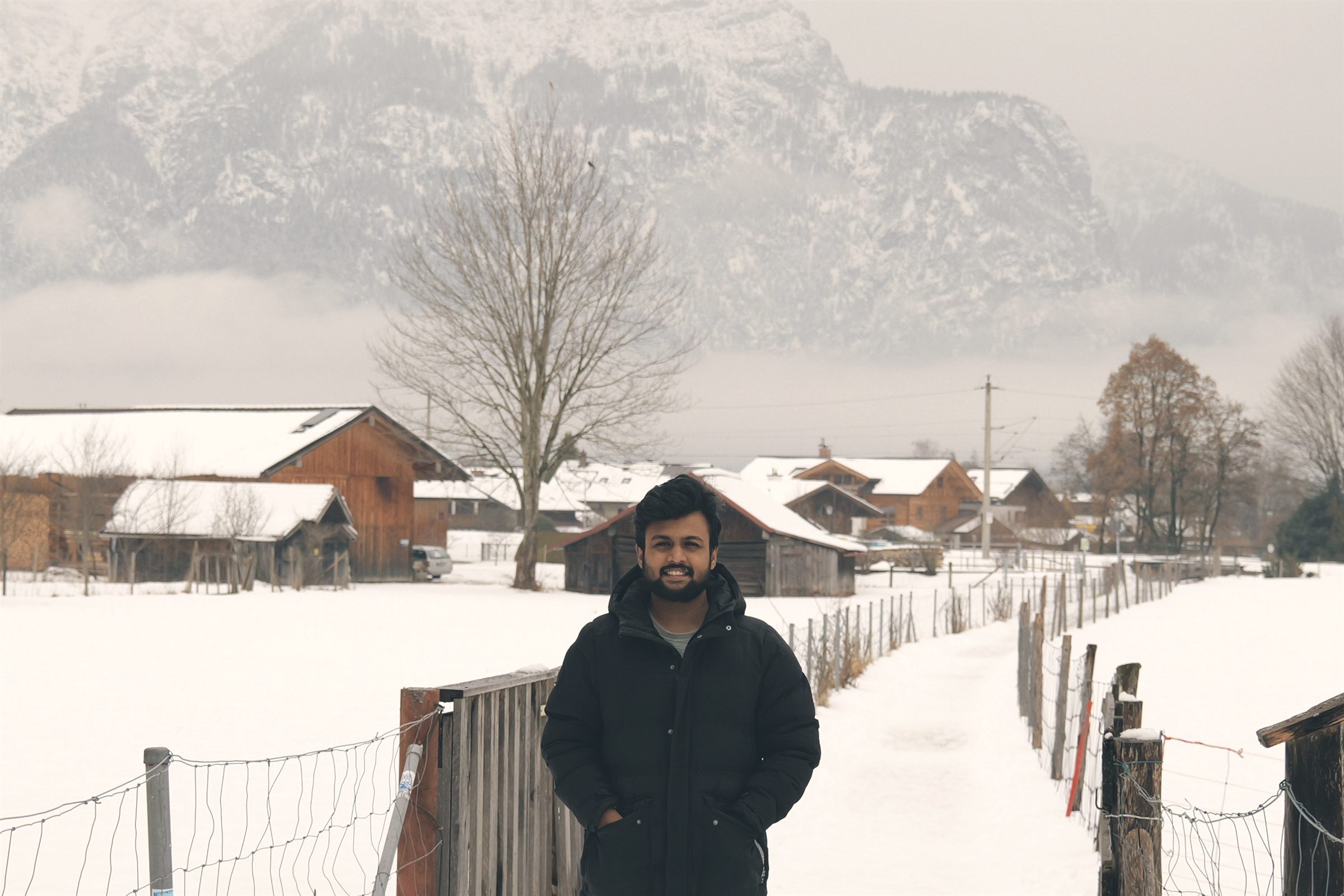 Ibin Mathew Biju standing on a snow-covered path in an Alpine village