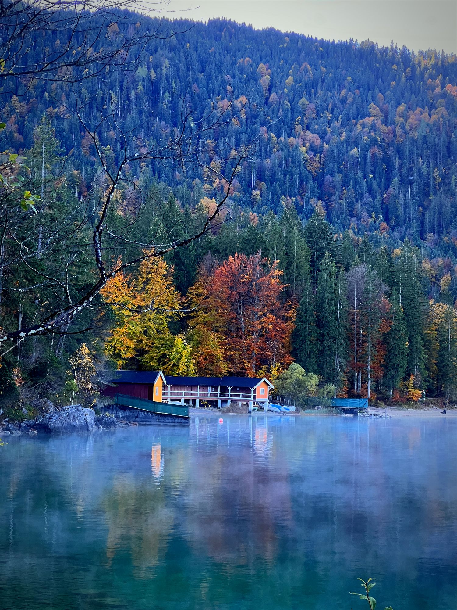 Alpine lake and autumn forest with a boathouse