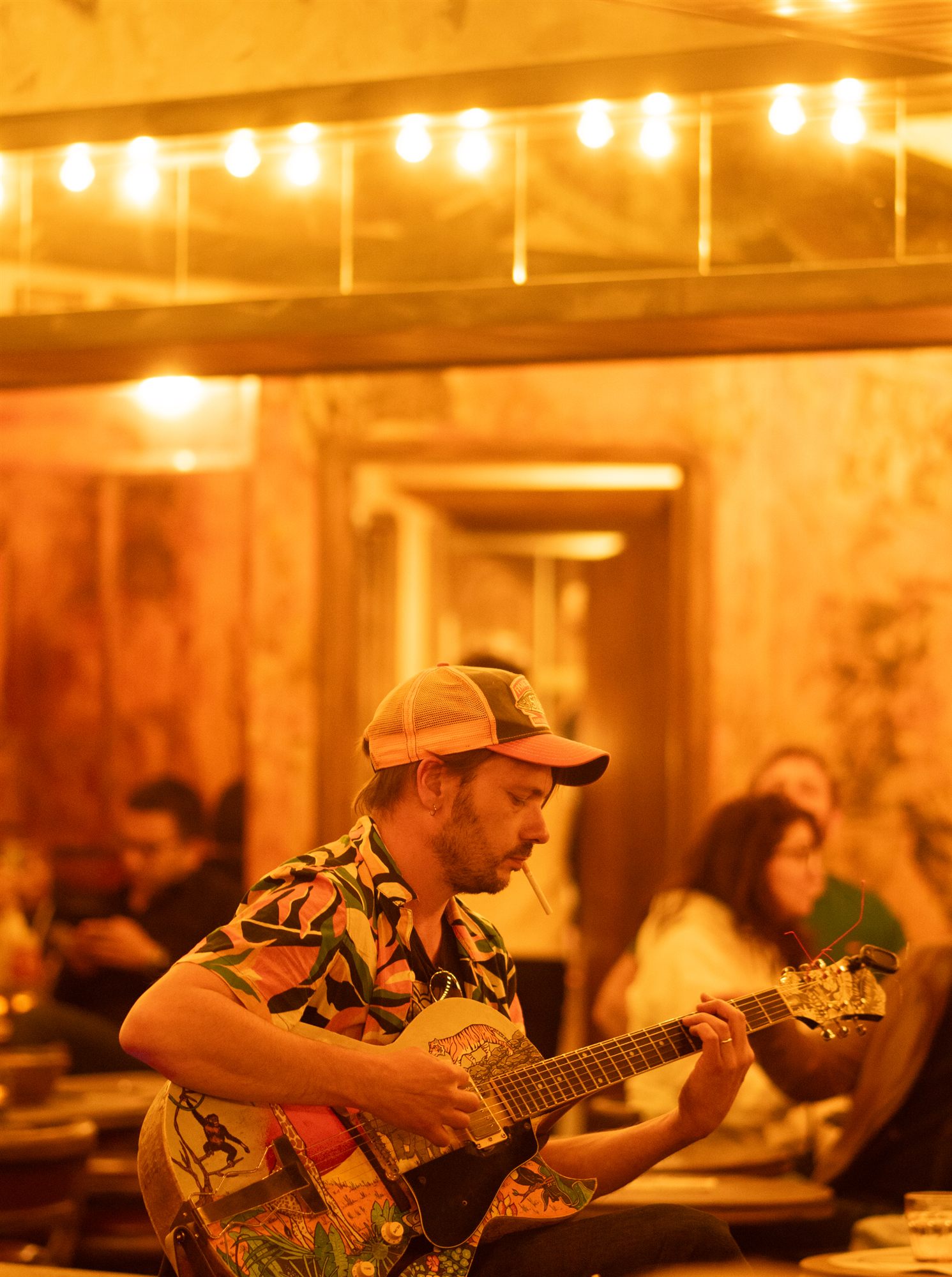 Musician playing under café string lights